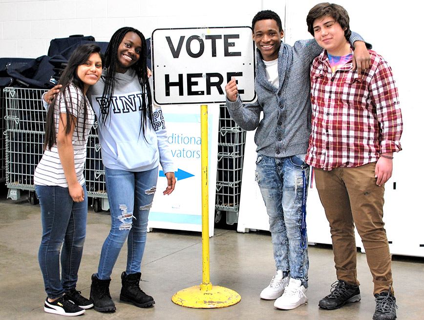 students with a sign that says vote here