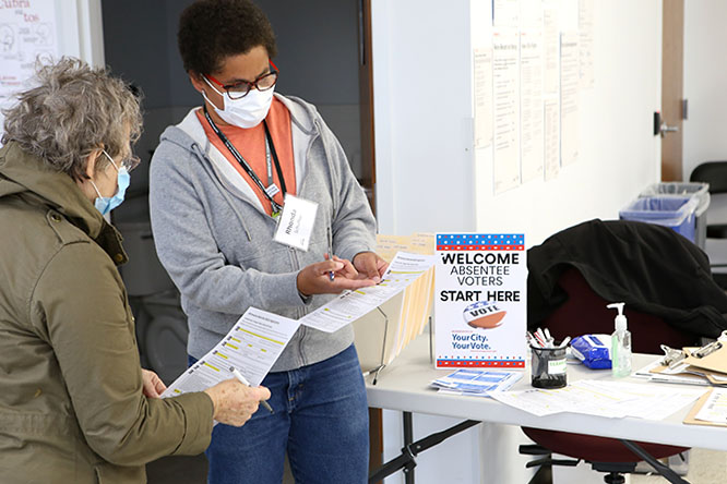 election worker checking a voter in at the early vote center, showing them the absentee ballot application form