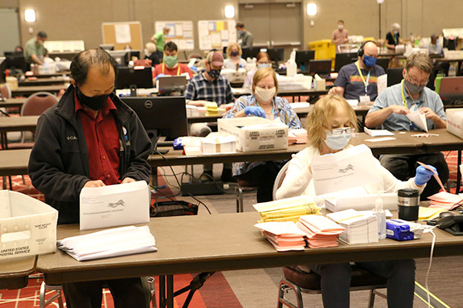 election workers stuffing mail ballot envelopes with materials