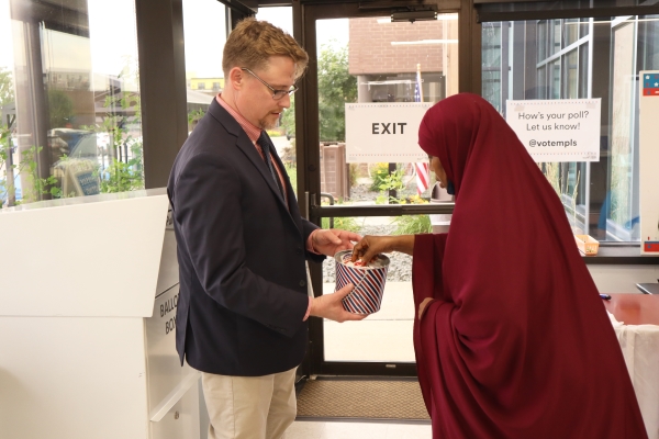 Election worker handing sticker to voter at Early Voting Center