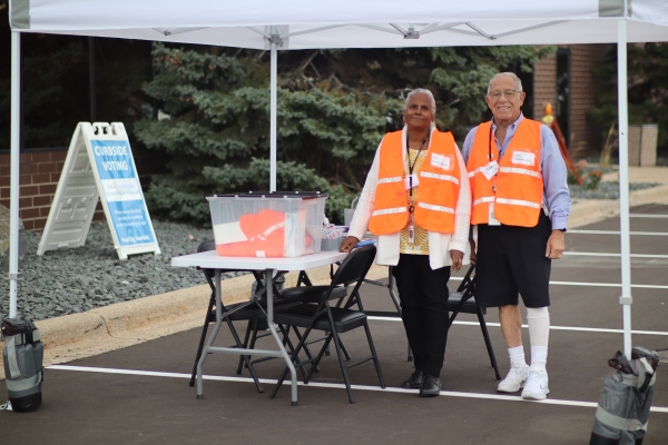 Election workers in orange vests assisting with curbside voting