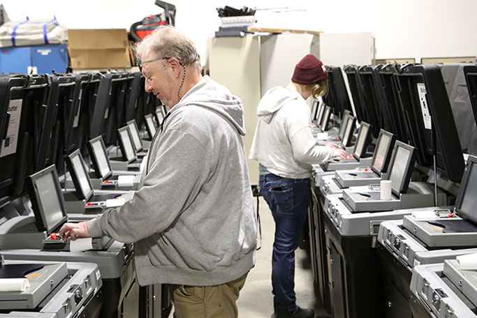 election workers testing tabulators in the warehouse